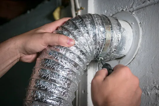 Hands tightening a clamp on a foil flex duct connection