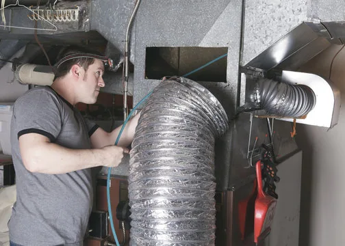 Technician cleaning flex duct at a furnace plenum